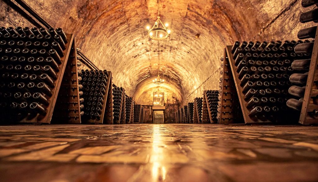 Rows of oak barrels in an elegant French wine cellar, symbolizing the exclusive experiences offered on Œlysium’s luxury wine tours across France’s renowned regions.