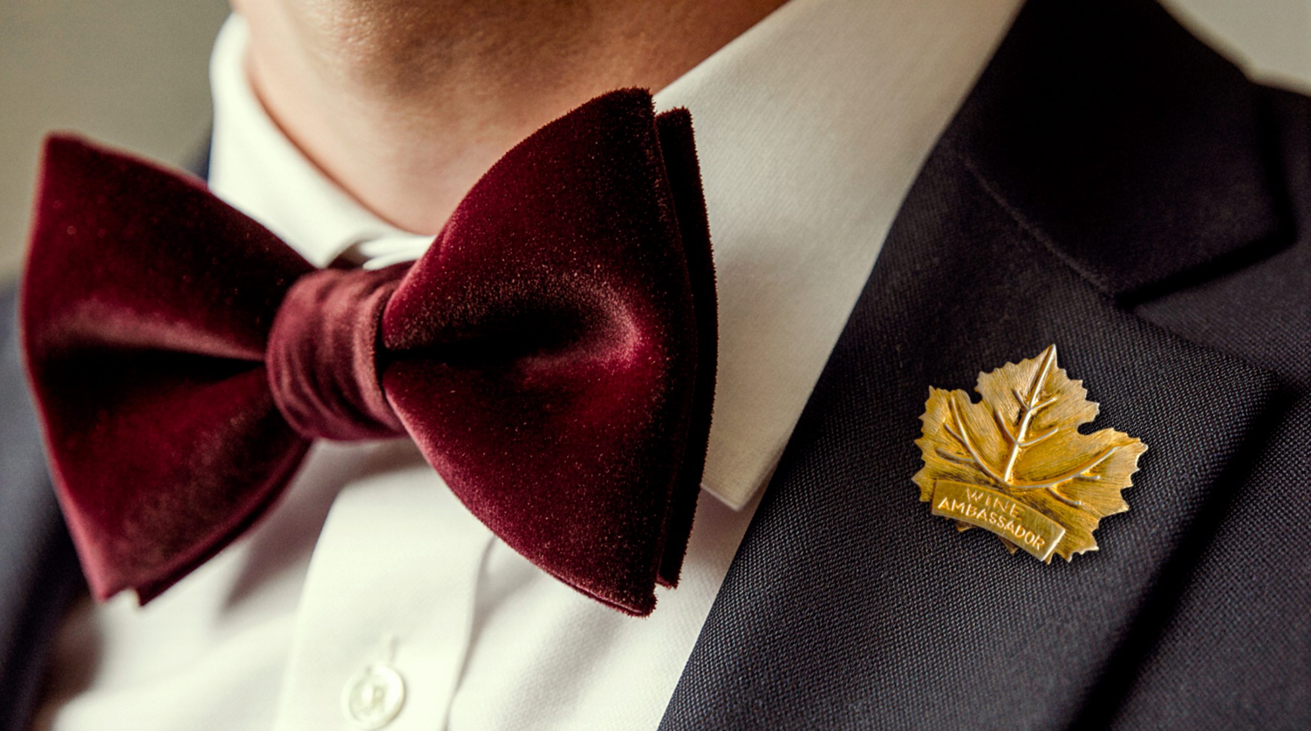 close-up of œlysium wine ambassador wearing a gold leaf pin and burgundy bow tie